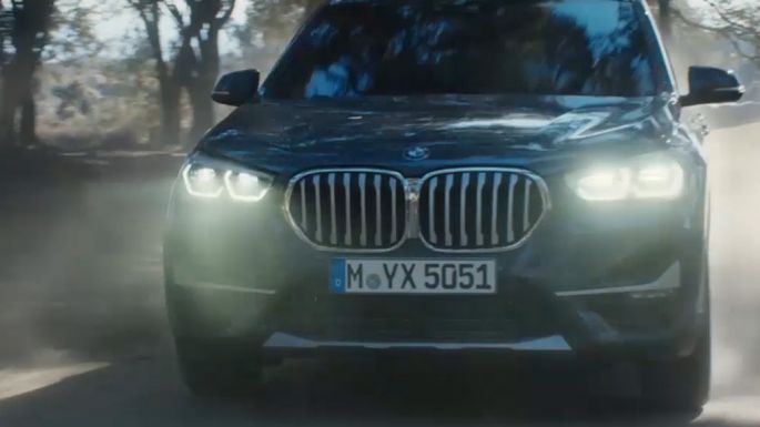 BMW X1, three-quarter front view. BMW X1, three-quarter front view driving in front nature scenery.