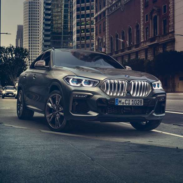 BMW X6, suspension M adaptative Professional. La BMW X6 vue de trois quarts avant devant un décor urbain.