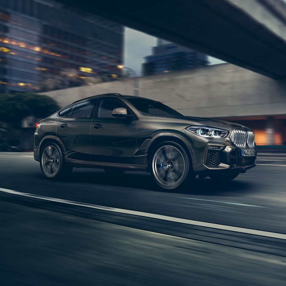 BMW X6. La BMW X6 vue de trois quarts avant en marche devant un décor urbain.