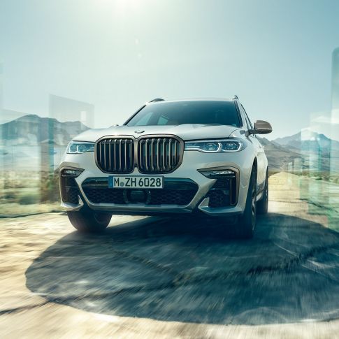 BMW X7 M50d, vue en contre-plongée diagonale BMW X7 M50d : vue en contre-plongée diagonale d’une BMW X7 de couleur blanche en mouvement