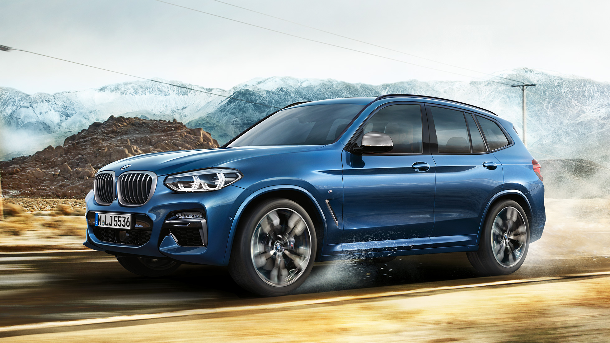 BMW X3 M40i, plan moyen de la jante et de l’aile devant un paysage montagneux BMW X3 M40i, plan moyen de la jante et de l’aile devant un paysage montagneux