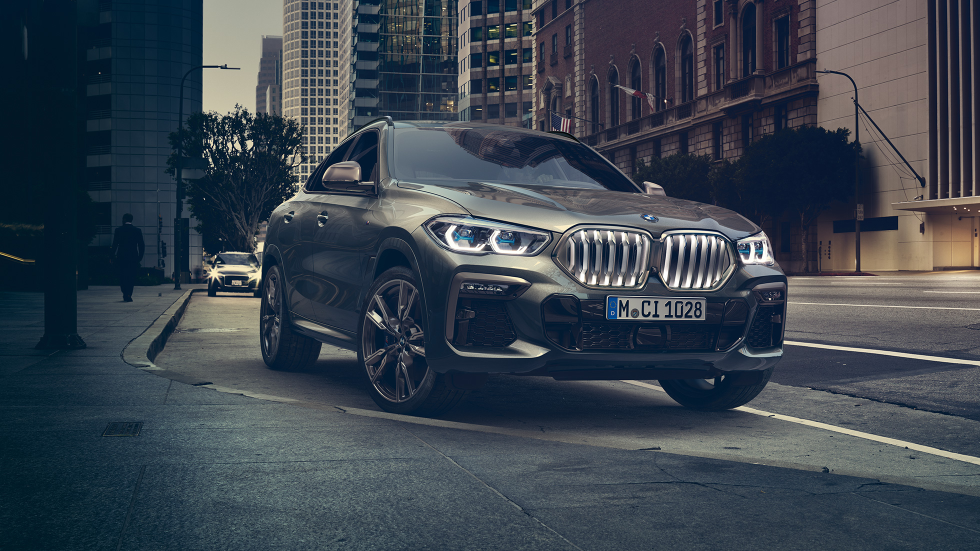 BMW X6, suspension M adaptative Professional. La BMW X6 vue de trois quarts avant devant un décor urbain.