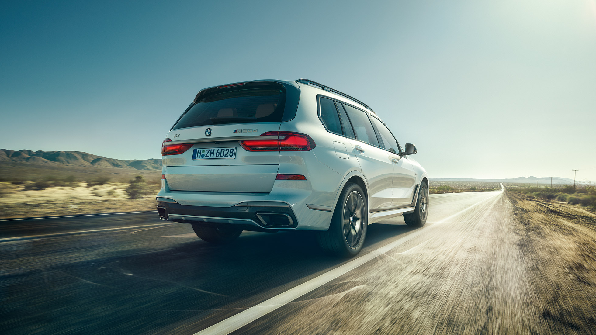 BMW X7 M50d, vue arrière BMW X7 M50d : Vue arrière d’une BMW X7 de couleur blanche en mouvement