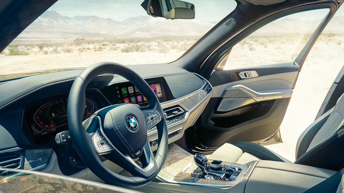 Intérieur de la BMW X7 Intérieur de la BMW X7 : Vue de l’extérieur de la première rangée de sièges, centrée sur le volant, le combiné des instruments et les sièges en cuir.