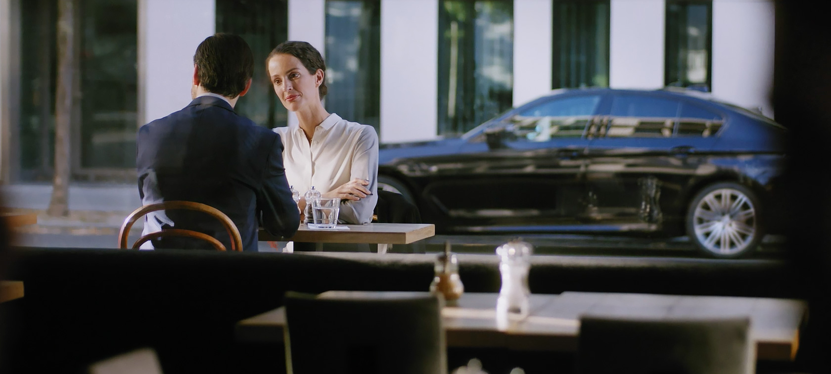 Service Après-vente entreprises BMW : Un homme et une femme sont assis dans un café Service Après-vente entreprises BMW : Un homme et une femme sont assis dans un café, une BMW apparaît à l’arrière-plan